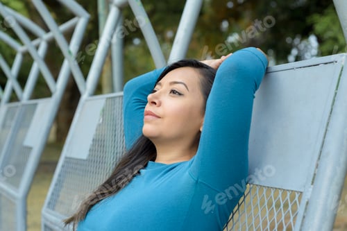 Preview: Woman sitting on a bench in the park with a bored expression.