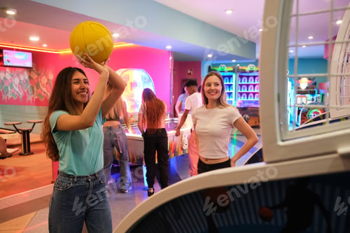 Preview: Young women playing basketball arcade game in entertainment center