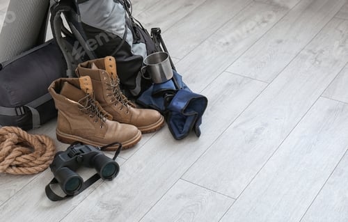 Preview: Set of camping equipment with sleeping bag on wooden floor. Space for text