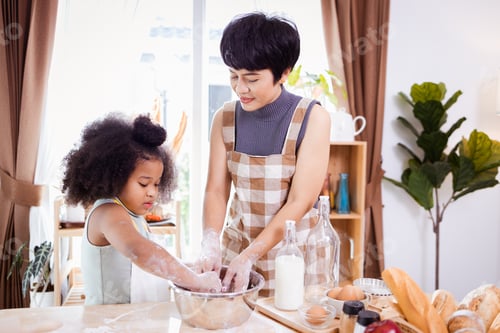 Preview: Happy African American mother and daughter having fun while preparing cookie dough at home