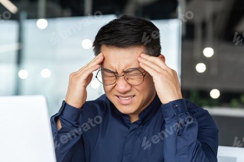 Preview: Close-up photo of sick Asian businessman having severe headache, male boss in glasses working inside