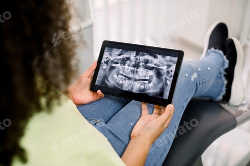 Preview: African American teen girl, sitting in dental chair at modern clinic,