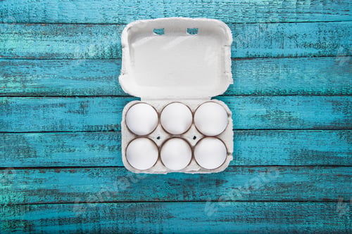Preview: Top view of raw chicken eggs in open carton box on table