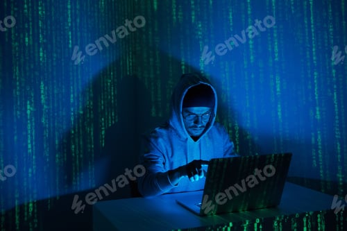 Preview: Young man in hooded shirt using computer against dark background