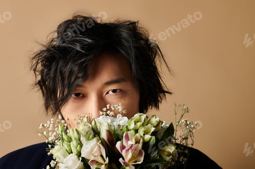 Preview: Stylish Asian man with flowers showcasing spring fashion in creative studio setting