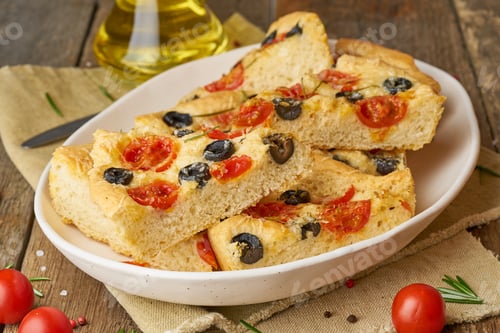 Preview: Focaccia, pizza in plate with tomatoes, olives and rosemary. Chopped Italian flat bread.