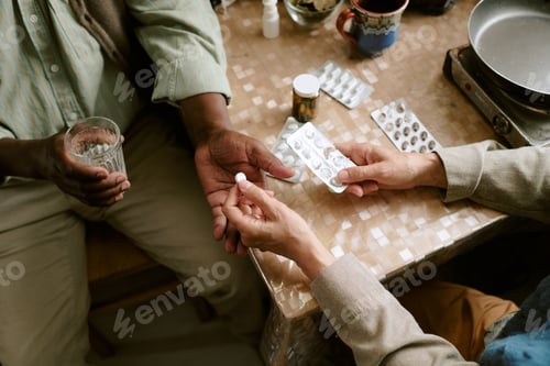 Preview: Senior Multiethnic Couple Taking Medication Together at Home Table
