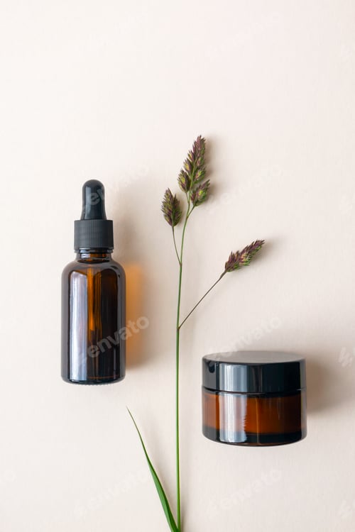 Preview: Mockup moisturizer cream and serum in brown glass bottle and jar and meadow herb on light beige