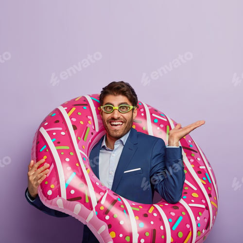 Preview: Photo of handsome cheerful man with dark hair, raises palm, wears goggles and suit, wants to swim in