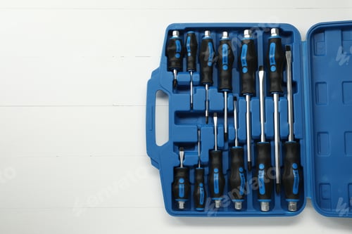 Preview: Set of screwdrivers in open toolbox on white wooden table, top view. Space for text