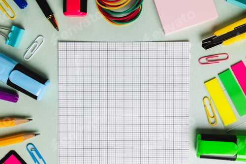 Preview: Composition of checked sheet and frame made of school tools on green surface