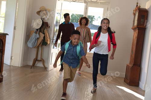 Preview: Happy african american couple with son and daughter back from school embracing and smiling at home