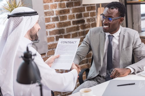 Preview: Arabian businessman holding contract and shaking hands with african american partner