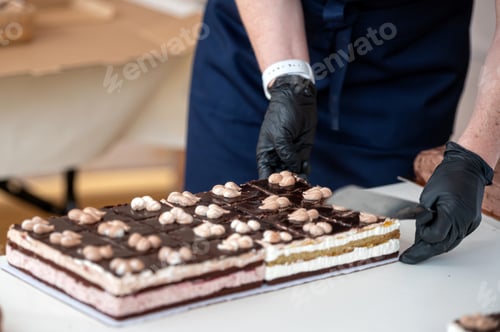 Preview: Baker cutting chocolate cake with white icing.