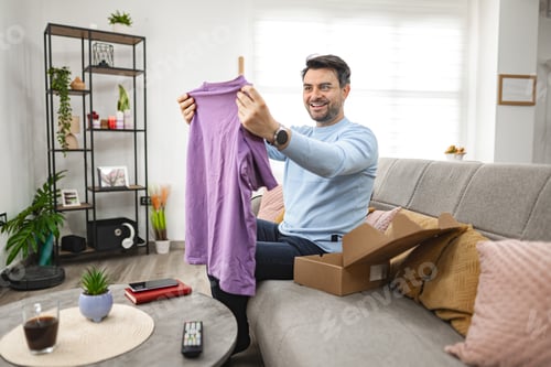 Preview: Man opens the cardboard package and looks at the new T-shirt