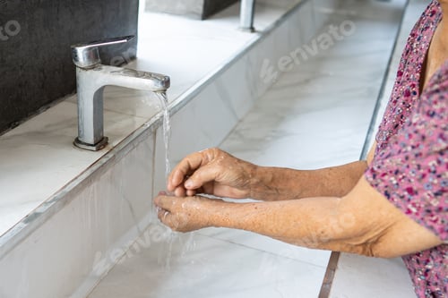 Preview: Asian senior woman patient washing hand to clean in toilet bathroom at nursing hospital.