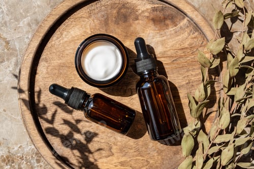 Preview: Amber glass bottles and jars with natural cosmetics and eucalyptus on tray on table in bathroom