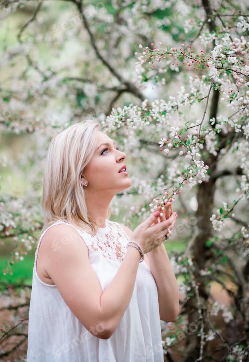 Preview: Close up portrait of attractive woman holding a flower and looking up deep in thought