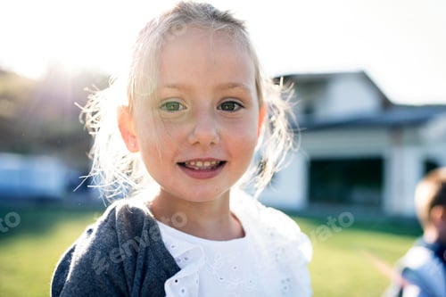 Preview: Front view of small girl standing outdoors, looking at camera.