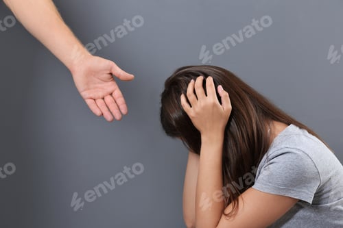 Preview: Man giving helping hand to depressed woman on gray background