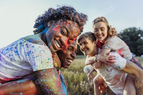 Preview: Happy Young Multiethnic Couples Piggybacking at Holi Festival