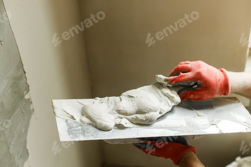 Preview: Plasterer Smoothing Plaster with Trowel on Wall