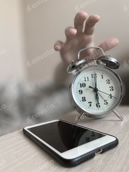 Preview: Alarm clock in the hand of a sleeping man
