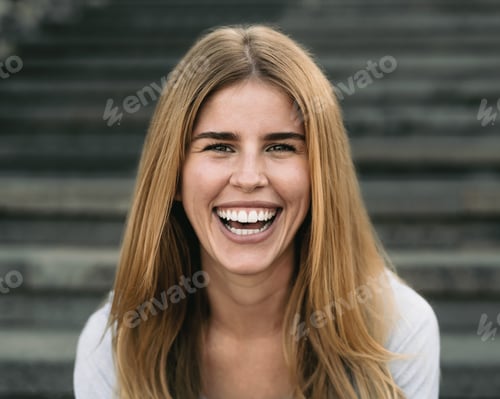 Preview: Happy young woman smiling into the camera while sitting on urban stairs