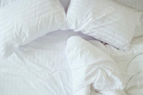 Preview: Top view of messy bedding sheets and pillows.