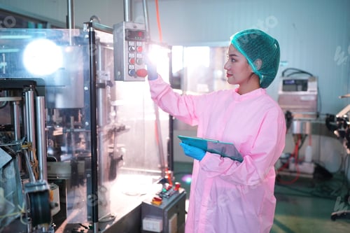 Preview: worker controlling the work of machine in production line at beverage industry.