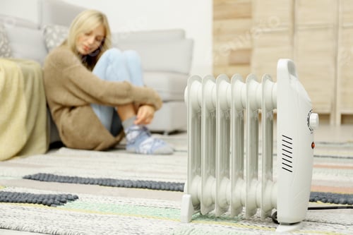 Preview: Electric heater and blurred young woman on background. Space for text