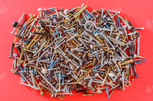 Preview: Isolated pile of screws of different types on red color background.