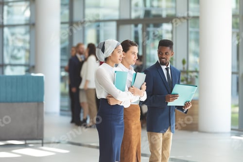 Preview: Young business executives standing with files in lobb