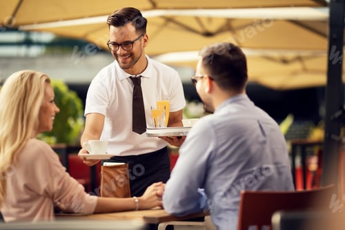 Preview: Happy waiter serving guests and giving them coffee in a cafe.