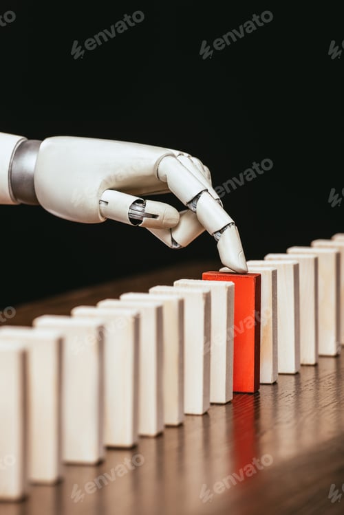 Preview: robotic hand picking red wooden brick from row of blocks on desk isolated on black