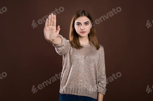 Preview: Close up portrait of a serious young woman showing stop gesture with hand