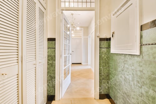 Preview: a hallway with white shuttered doors and green tile