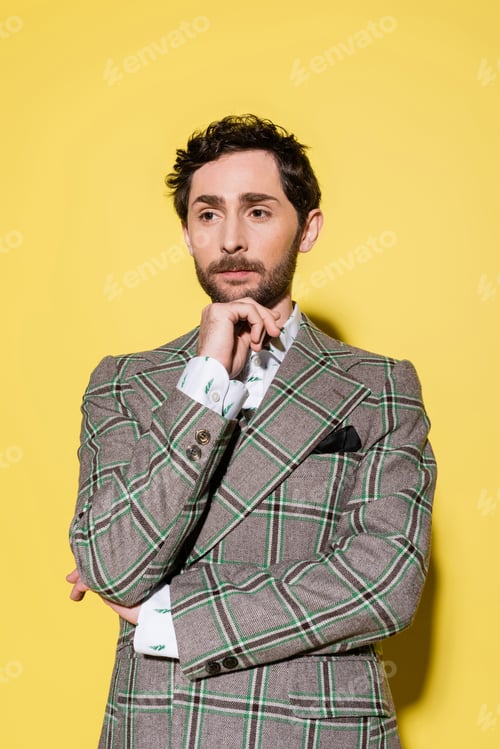 Preview: Portrait of stylish model in checkered jacket posing on yellow background
