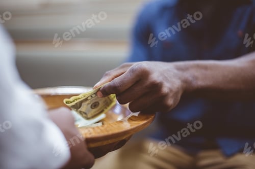 Preview: Closeup shot of a male donating money for church with a blurred background