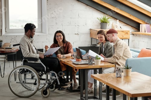 Preview: Two pairs of intercultural employees working in small groups by workplace