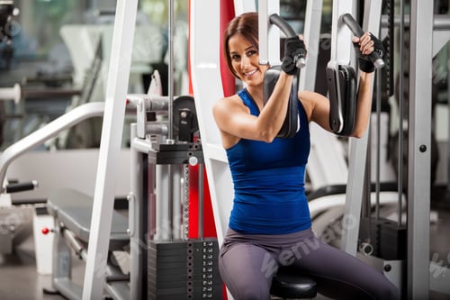 Preview: Beautiful hispanic woman doing back exercises at the gym