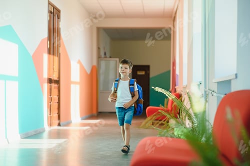 Preview: Portrait of a schoolboy standing with a backpack on an empty school hallway. Back to school.