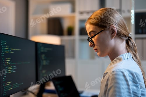 Preview: Caucasian young female software engineer working at night in the office.