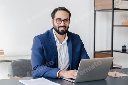 Bearded Man Works at Desk on Laptop