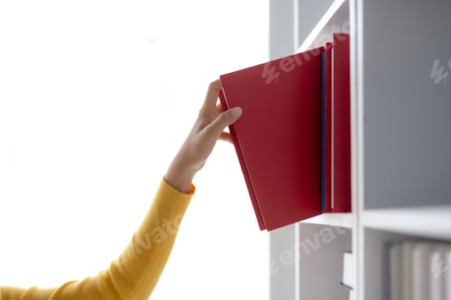 Preview: Woman selecting book from a bookshelf. University student selecting book from library in college.
