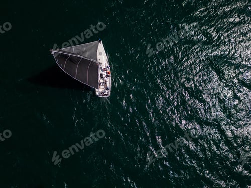 Preview: Top view of a sailing yacht with black sails moving through open sea