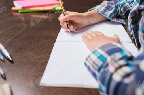 Preview: partial view of kid writing in notebook while doing homework