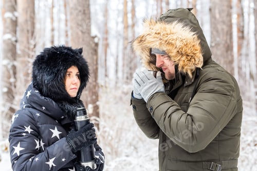 Preview: Season and walk concept - Happy couple drinking hot tea in winter forest