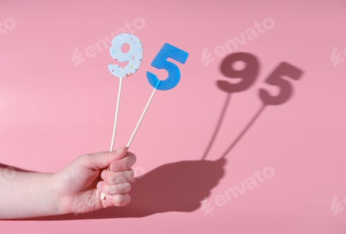 Preview: girl's hand holding a number 95 shaped lolipop. anniversary or birthday selebration