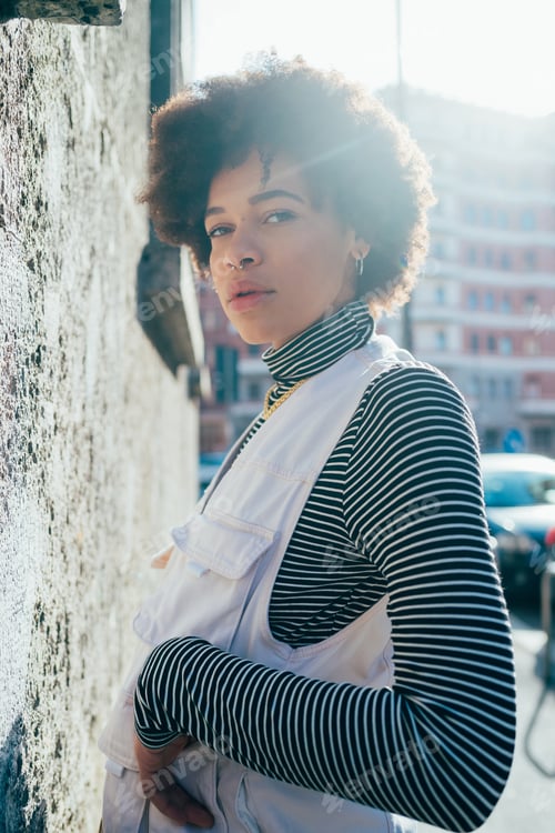 Preview: Young stylish curly hair diverse black woman outdoor backlight posing
